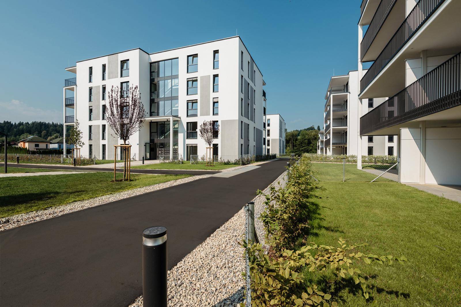 Neubauwohnungen mit moderner Architektur, Balkonen und gepflegten Außenanlagen an einem sonnigen Tag.