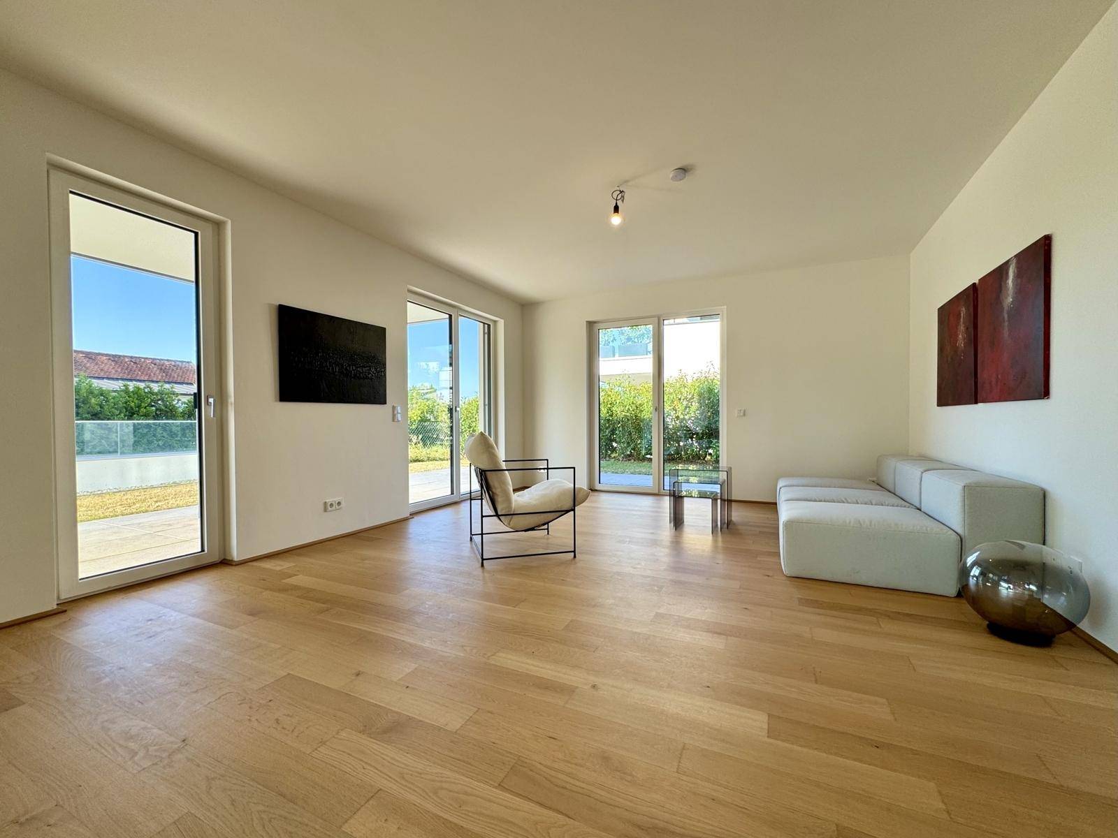 Geräumiges Wohnzimmer mit Eichenparkett, großen Fenstern und modernem Mobiliar, hell und einladend.