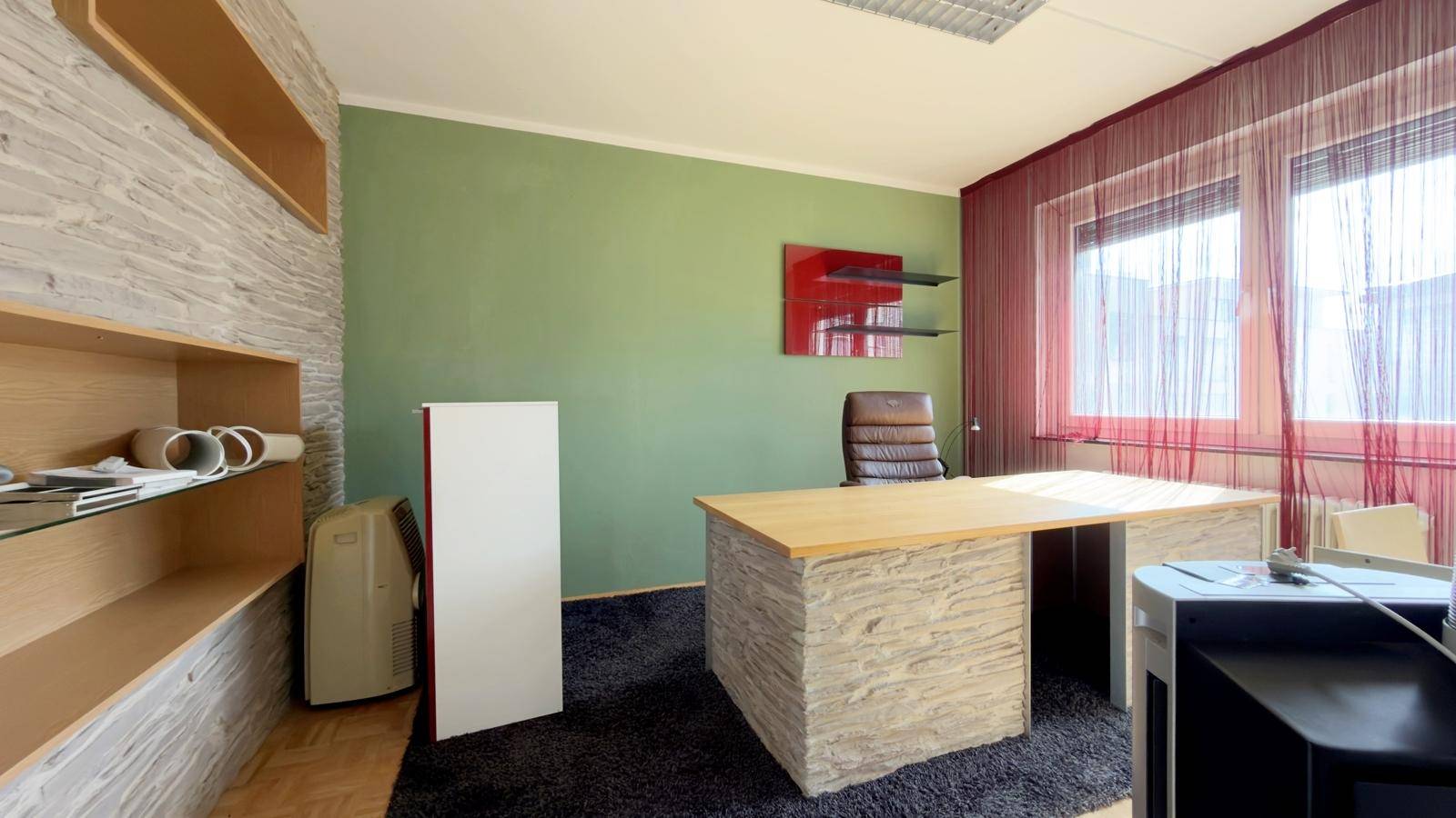 Modern gestaltetes Büro mit grüner Wand, Steinverkleidung und Teppichboden, bietet eine einzigartige Arbeitsatmosphäre.