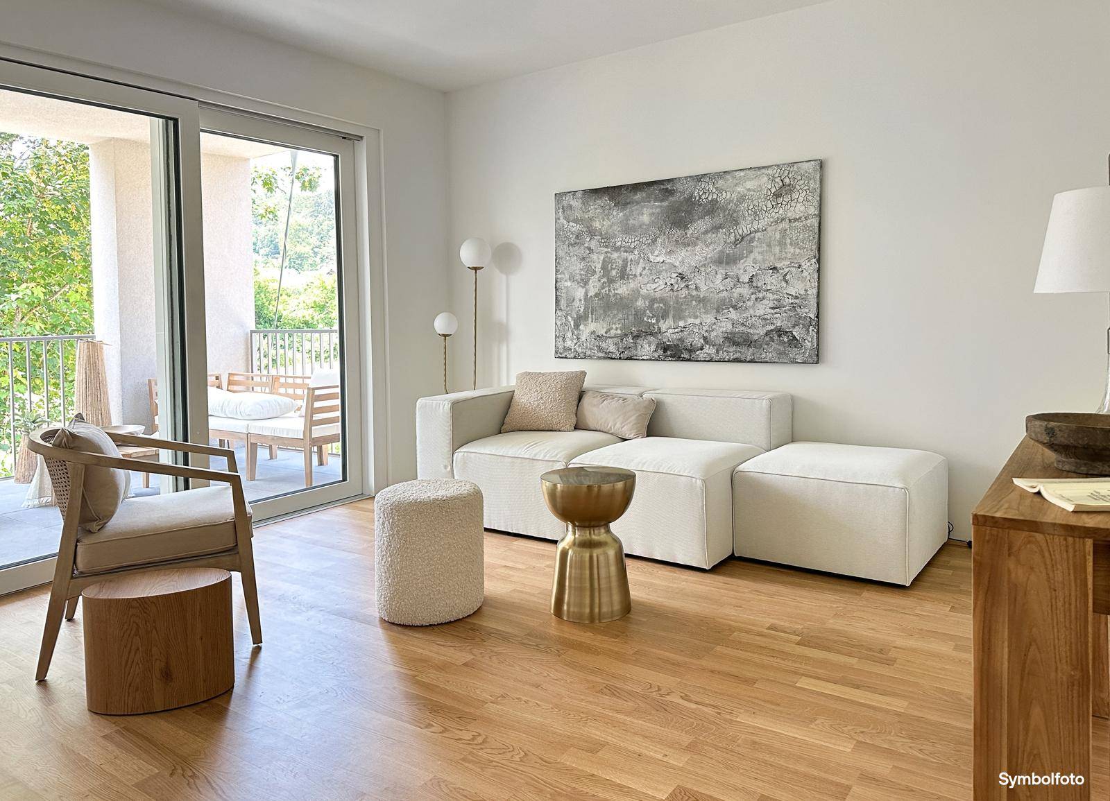 Helles Wohnzimmer mit Holzboden, modernem Sofa und direktem Zugang zu einem möblierten Balkon.