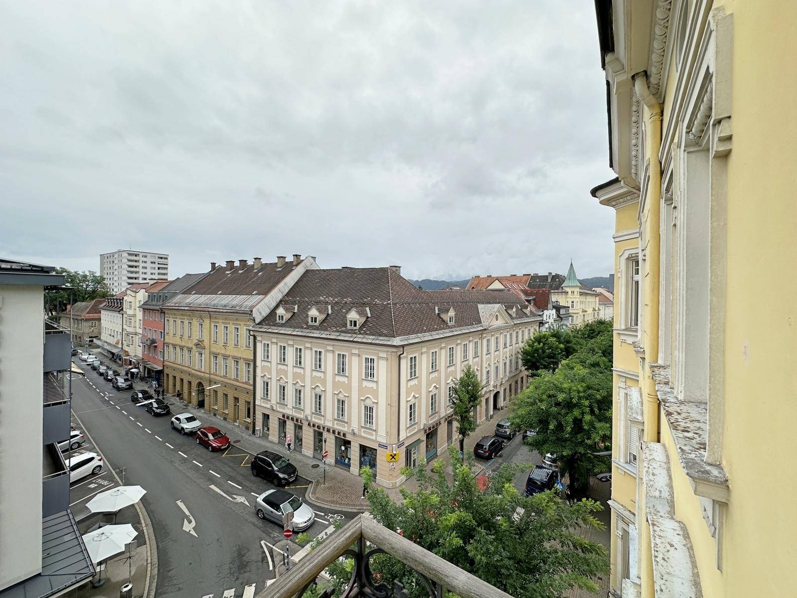 Panoramablick über die Stadtstraße mit Gebäuden, Bäumen und parkenden Autos.