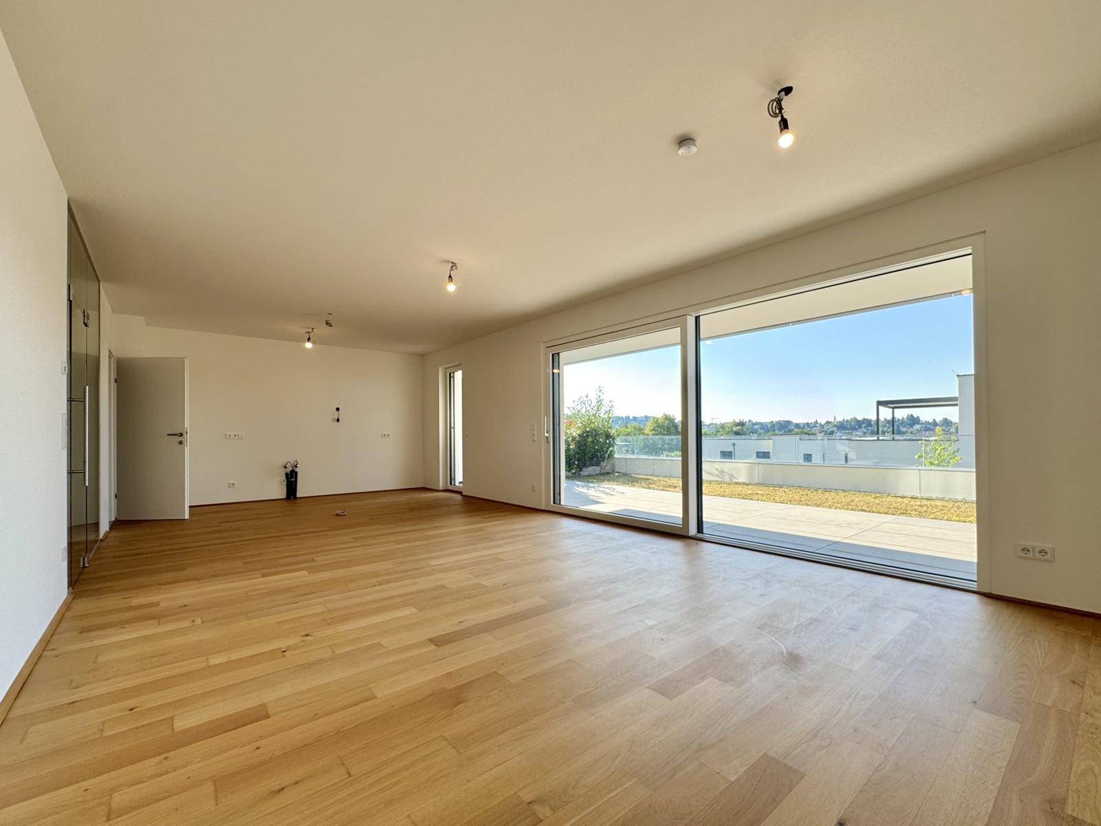 Helles und geräumiges Wohnzimmer mit Holzboden, großen Schiebetüren und Terrassenzugang.