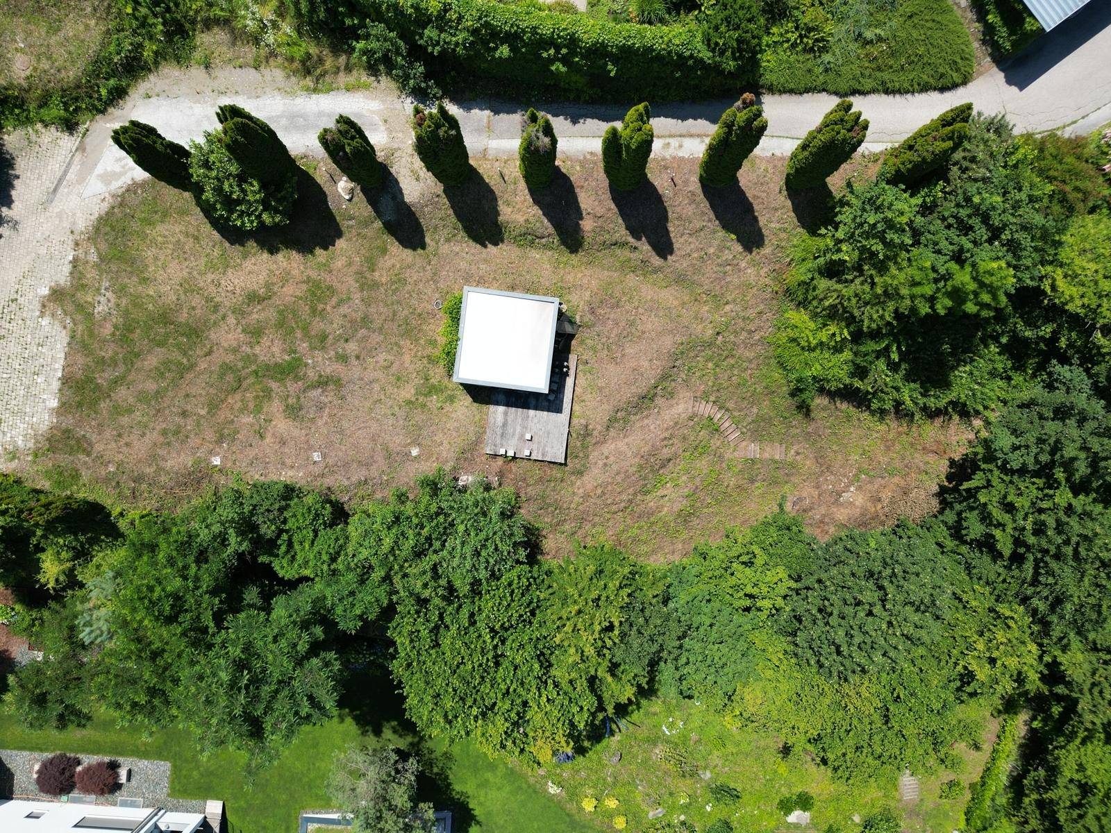 Senkrechte Luftaufnahme eines Grundstücks mit einem kleinen Schuppen und umliegender Vegetation.
