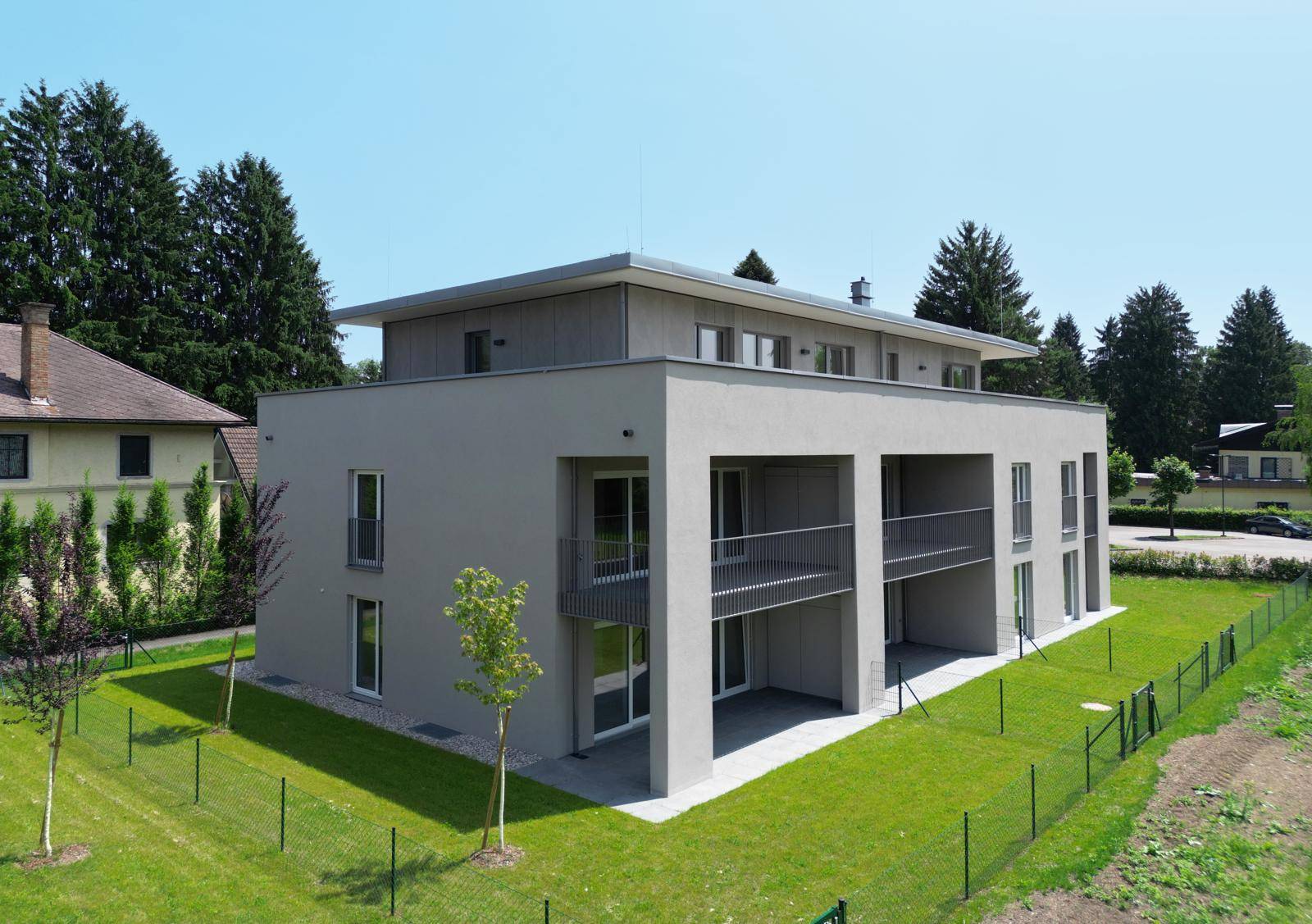 Ansicht eines modernen Wohngebäudes mit mehreren Balkonen und einer weitläufigen Rasenfläche.