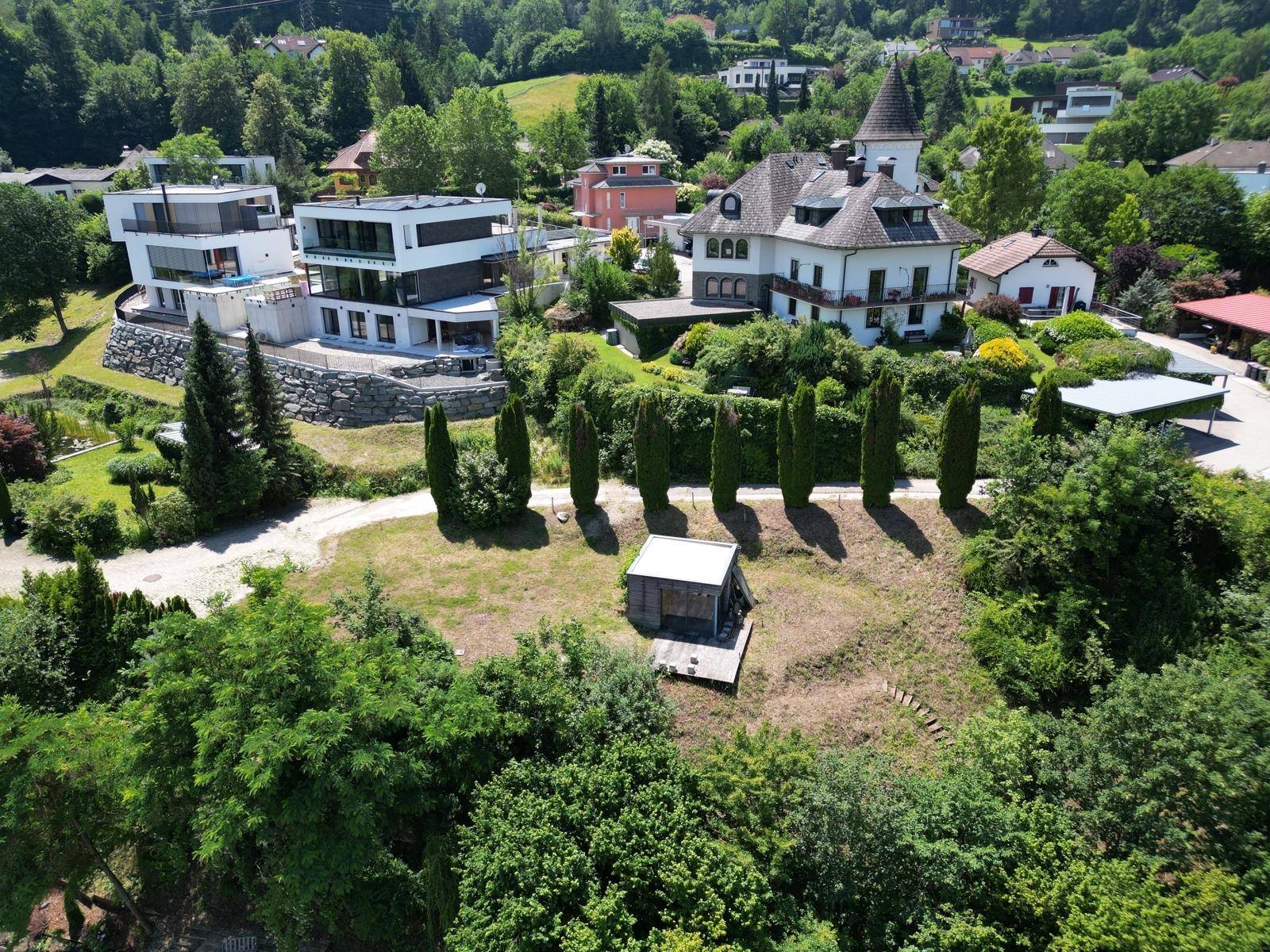 Luftaufnahme des Grundstücks mit Schuppen, umgeben von verschiedenen Wohngebäuden und viel Grün.