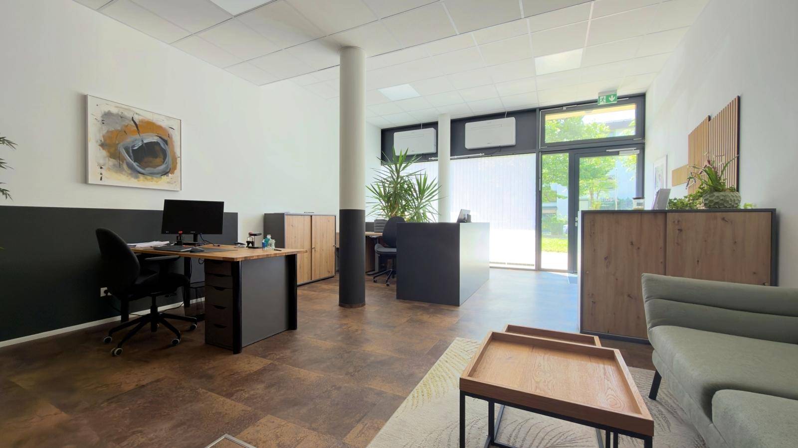 Modernes Büro mit Arbeitsplätzen, einem Empfangsbereich und einem Sofa für Besucher.