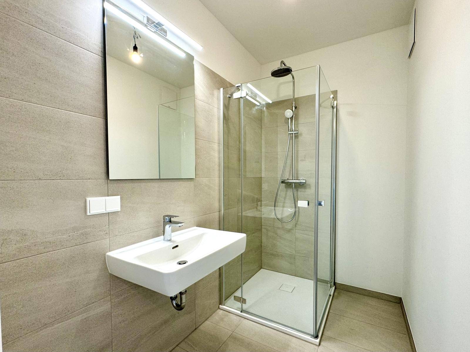 Modernes Badezimmer mit begehbarer Dusche, Wandwaschbecken und hellen Fliesen.
