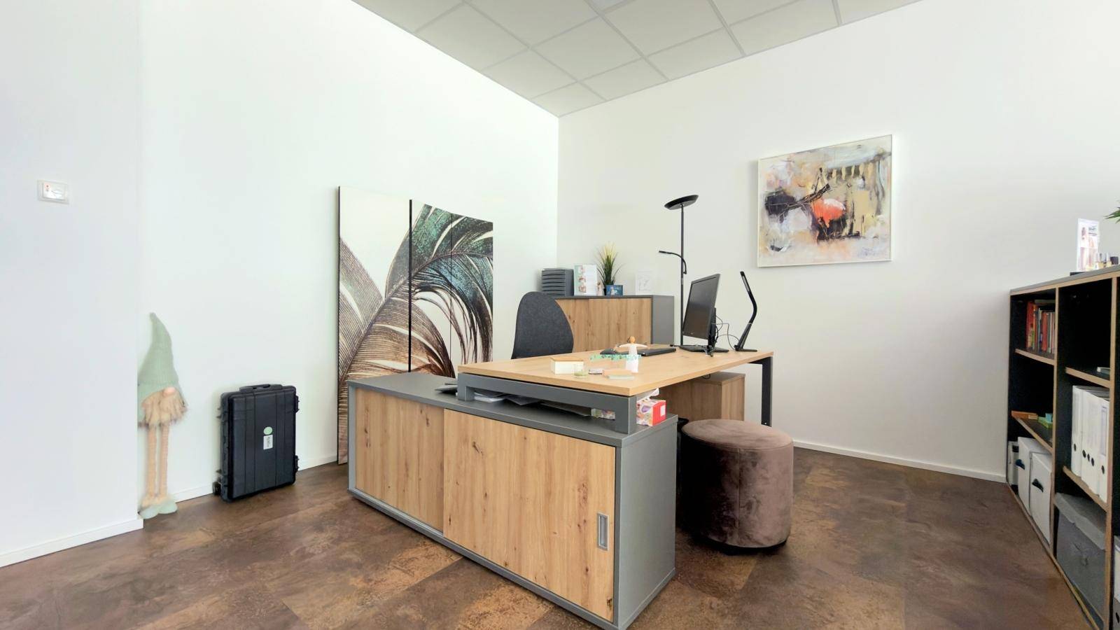 Geräumiger Arbeitsplatz mit Holzschreibtisch, Bürostuhl und einem Regal für Büromaterial.
