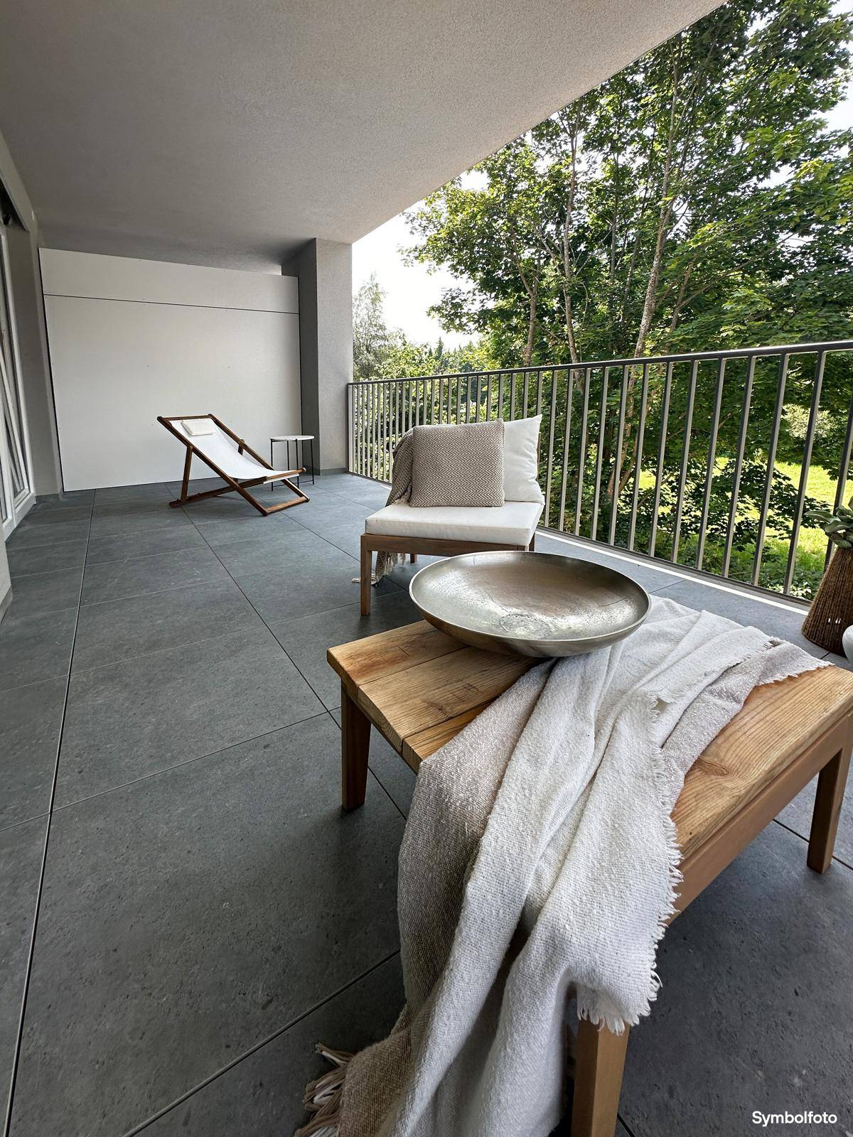 Detailansicht der Outdoor-Möbel und Dekoration auf dem Balkon mit Blick ins Grüne.