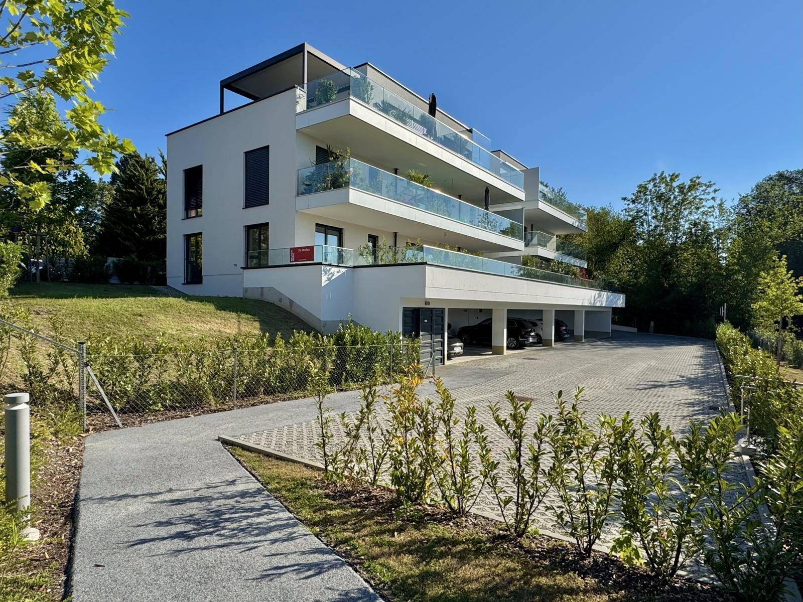 Modernes Wohngebäude mit mehreren Etagen, Balkonen und integrierter Tiefgarage.