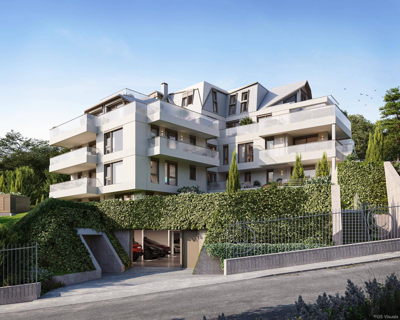Moderne Wohnanlage mit Tiefgaragenzufahrt, umgeben von üppiger grüner Bepflanzung.
