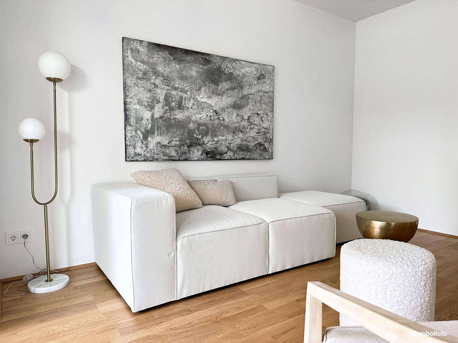 Detailansicht des modernen weißen Sofas und einer stilvollen Stehlampe im hellen Wohnzimmer.