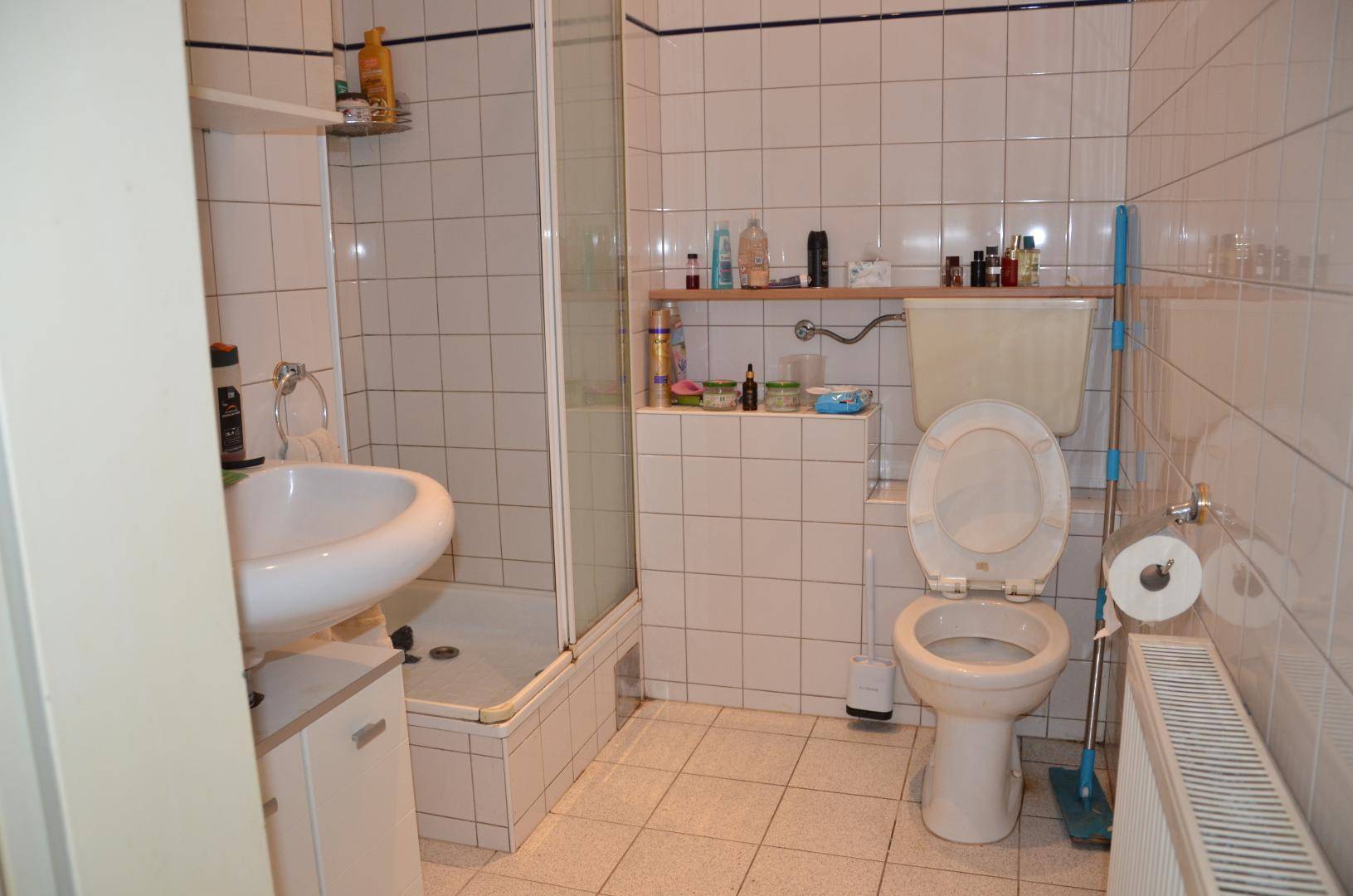 Gefliestes Badezimmer mit Duschkabine, WC und Waschbecken, praktisch und sauber gehalten.
