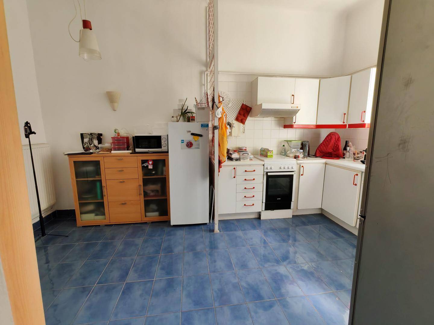 Funktionale Küche mit blauen Bodenfliesen, weißen Schränken und integrierten Geräten, bietet viel Stauraum.