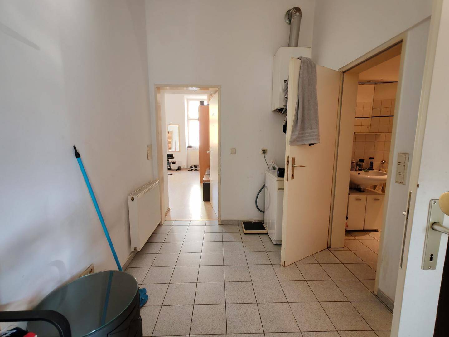 Flurähnlicher Bereich mit Fliesenboden, Heizung und Zugang zu weiteren Räumen, dient als Durchgang.