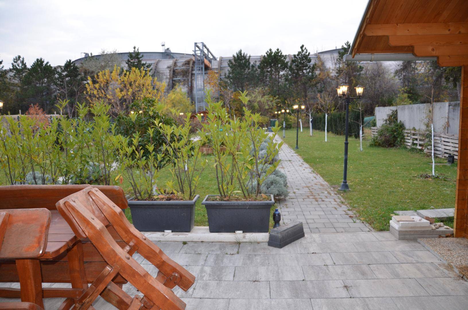 Weitläufiger Garten mit Holzsaunahaus, gepflastertem Weg und üppiger Bepflanzung.