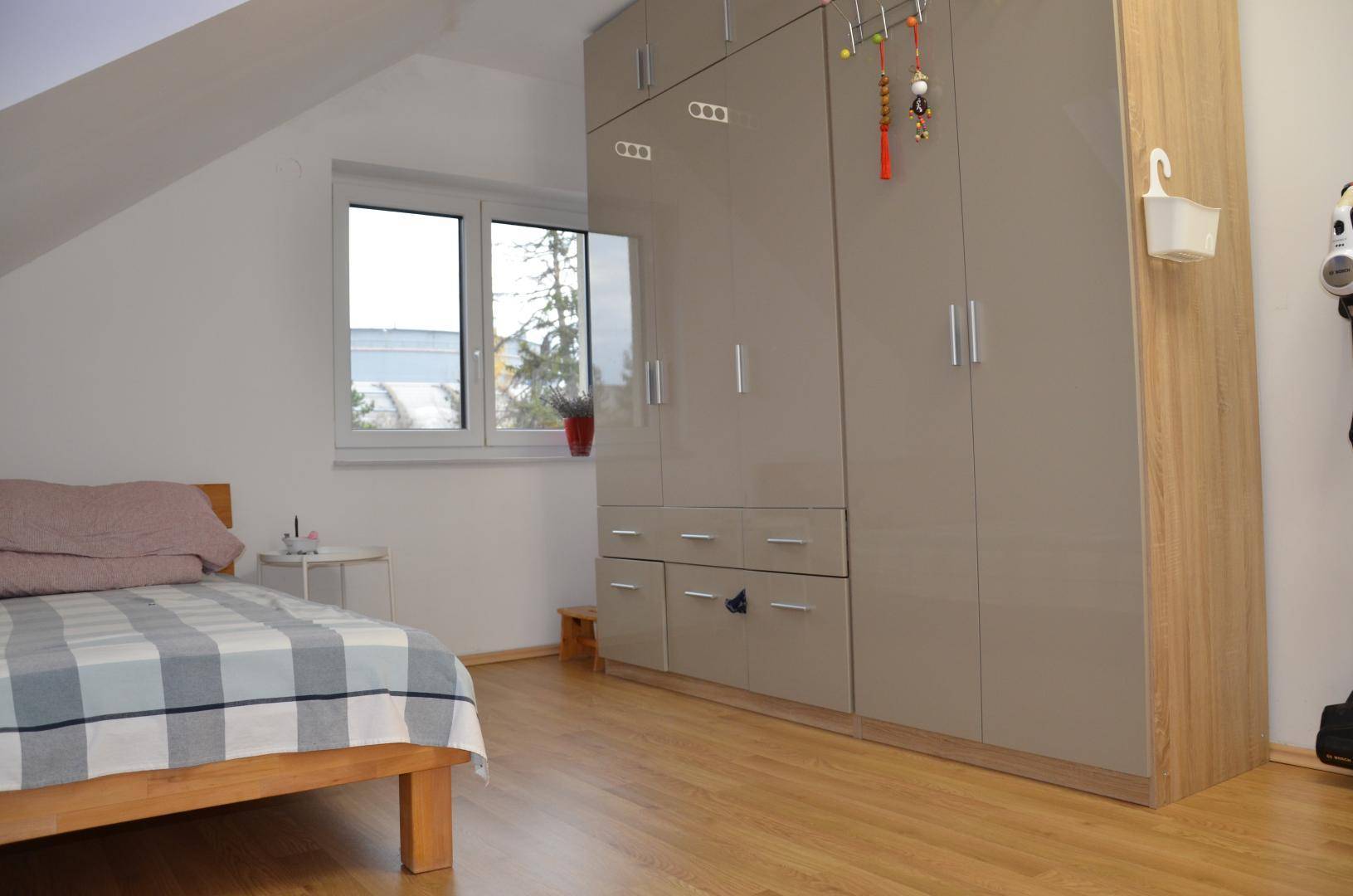 Helles Schlafzimmer mit Einzelbett und großem, modernem Kleiderschrank unter der Dachschräge.