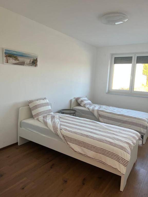 Schlafzimmer mit zwei Einzelbetten, Holzboden und einem Fenster mit Rollläden.