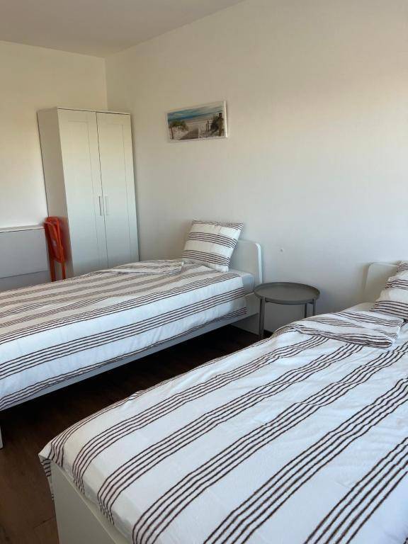 Helles Schlafzimmer mit zwei Einzelbetten, Holzboden und einem weißen Kleiderschrank.