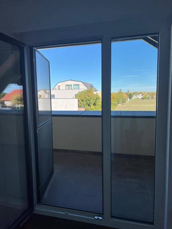 Blick aus einem Innenraum durch eine Glastür auf einen Balkon und die weite Landschaft.