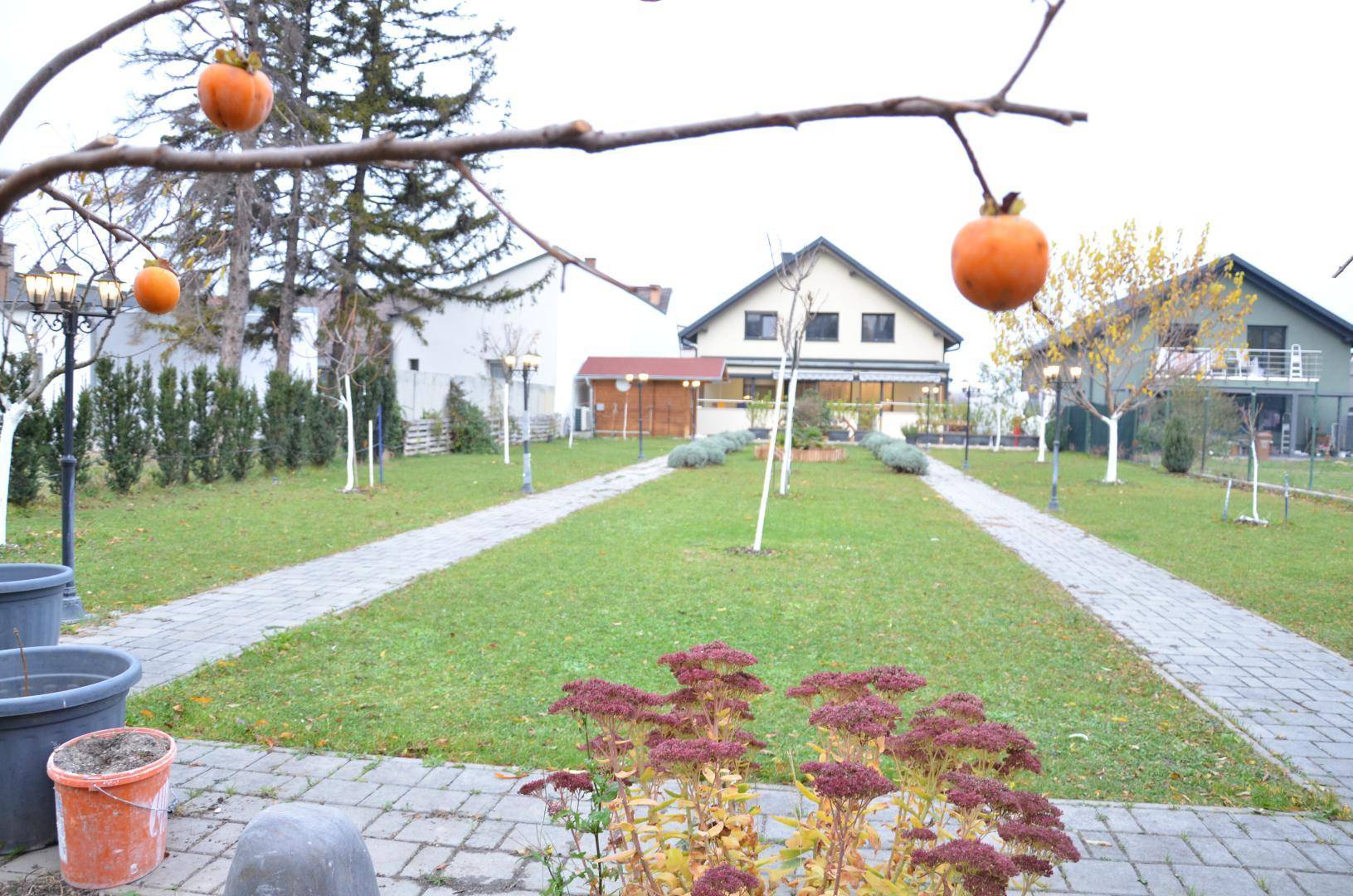 Großer Garten mit gepflasterten Wegen, Obstbäumen und dem Haupthaus im Hintergrund.