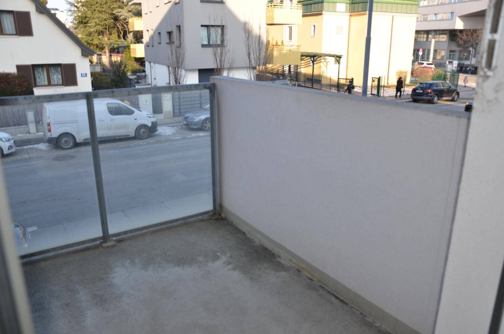 Kleiner Balkon mit Glasbrüstung und Blick auf die umliegende Wohngegend.