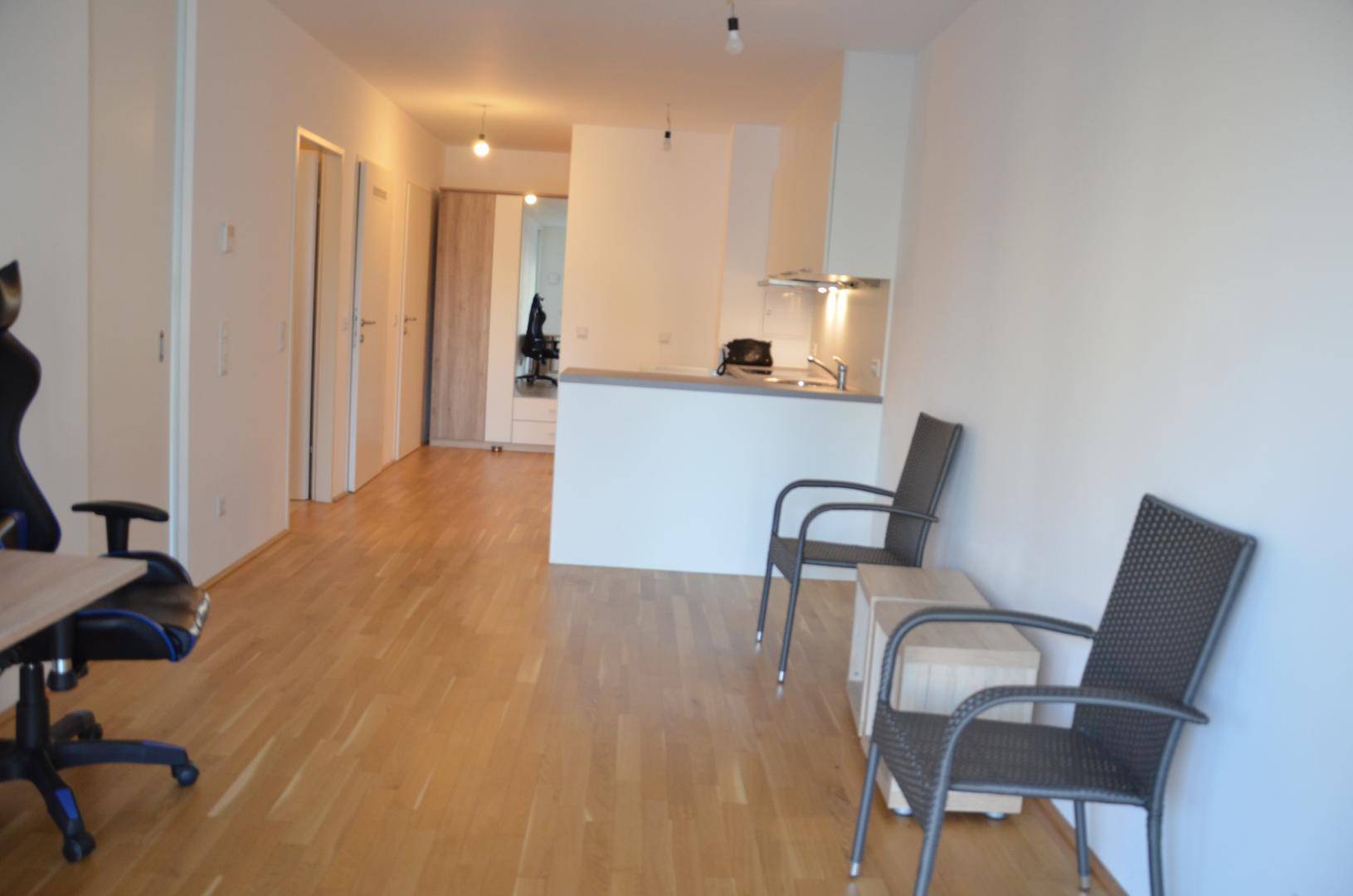 Geräumiger offener Wohnbereich mit Küchenzeile, Parkettboden und viel Tageslicht.