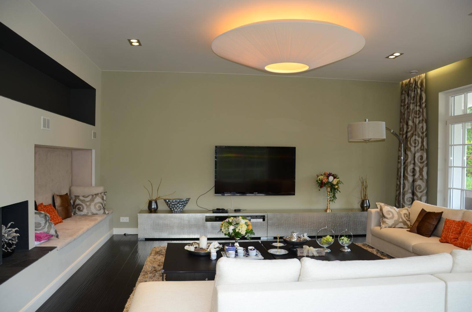 Modernes Wohnzimmer mit großem Flachbildfernseher, stilvoller Beleuchtung und gemütlicher Sitzecke.