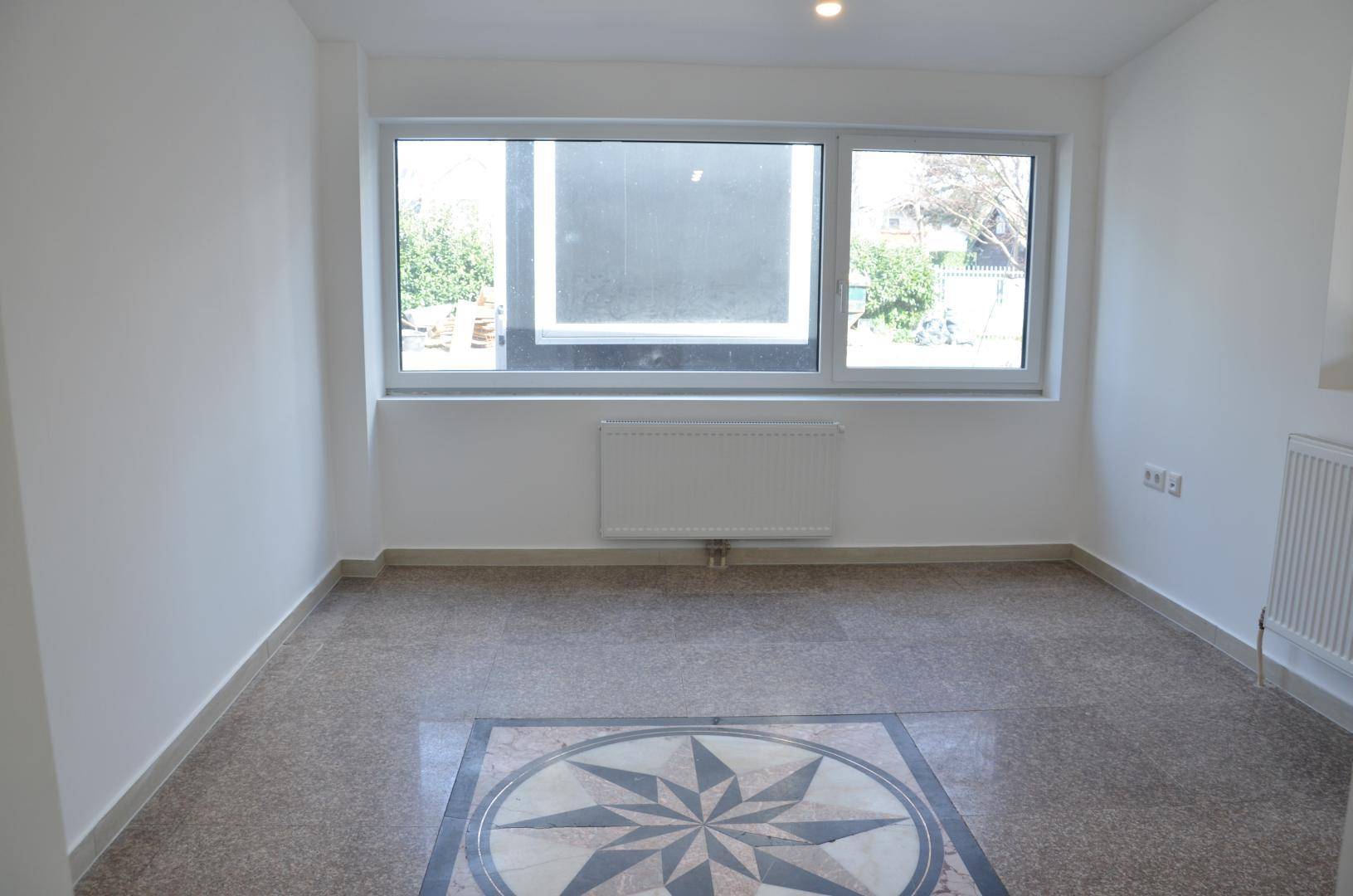 Heller, leerer Raum mit großen Fenstern und gemustertem Terrazzoboden, ideal für ein Büro.
