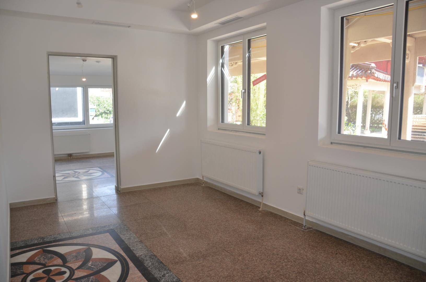 Geräumiger, heller Innenraum mit Terrazzoboden und Blick auf den Außenbereich durch große Fenster.