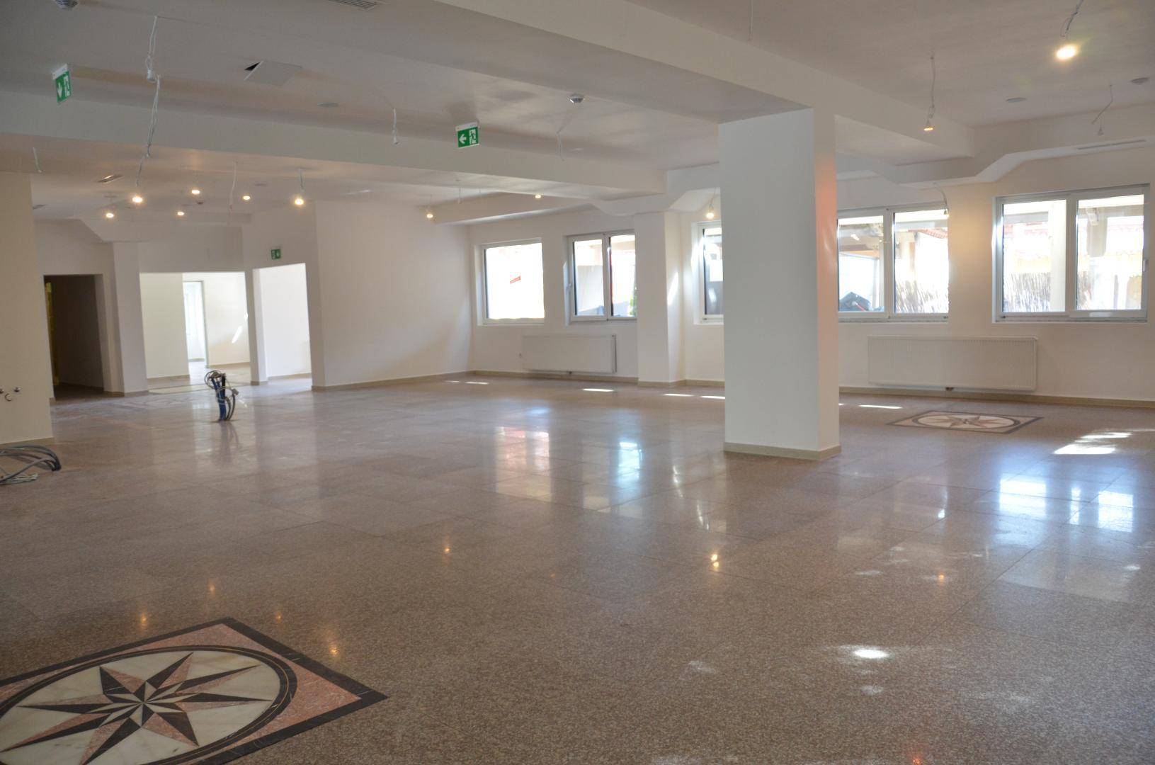 Weitläufiger, heller Gewerberaum mit Säulen, vielen Fenstern und glänzendem Terrazzoboden, sehr geräumig.