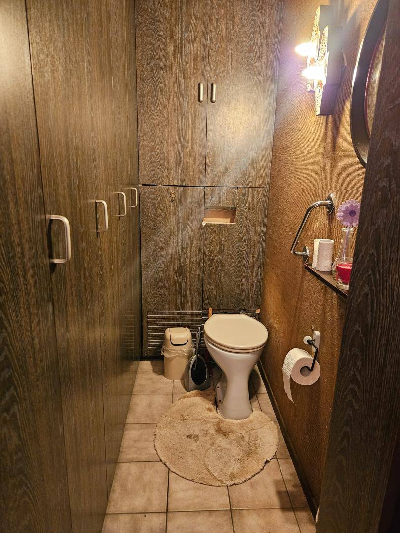 Kleines Gäste-WC mit dunklen Holzverkleidungen, Fliesenboden und Wand-WC.