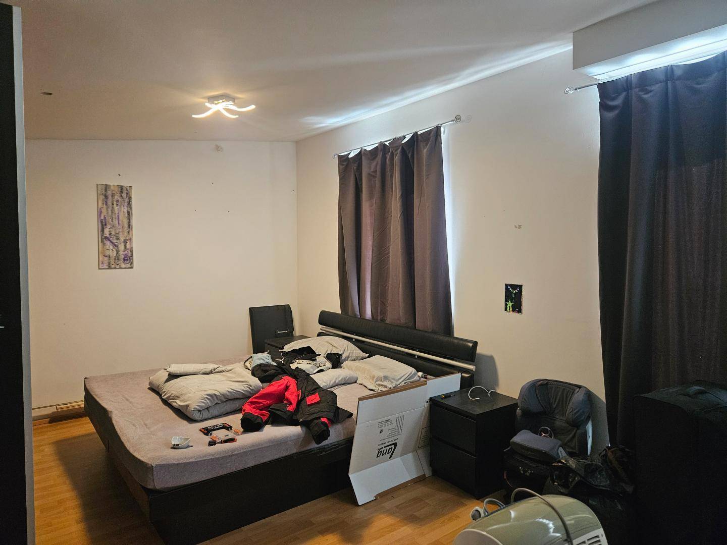 Schlafzimmer mit Doppelbett, dunklen Vorhängen und Klimaanlage.