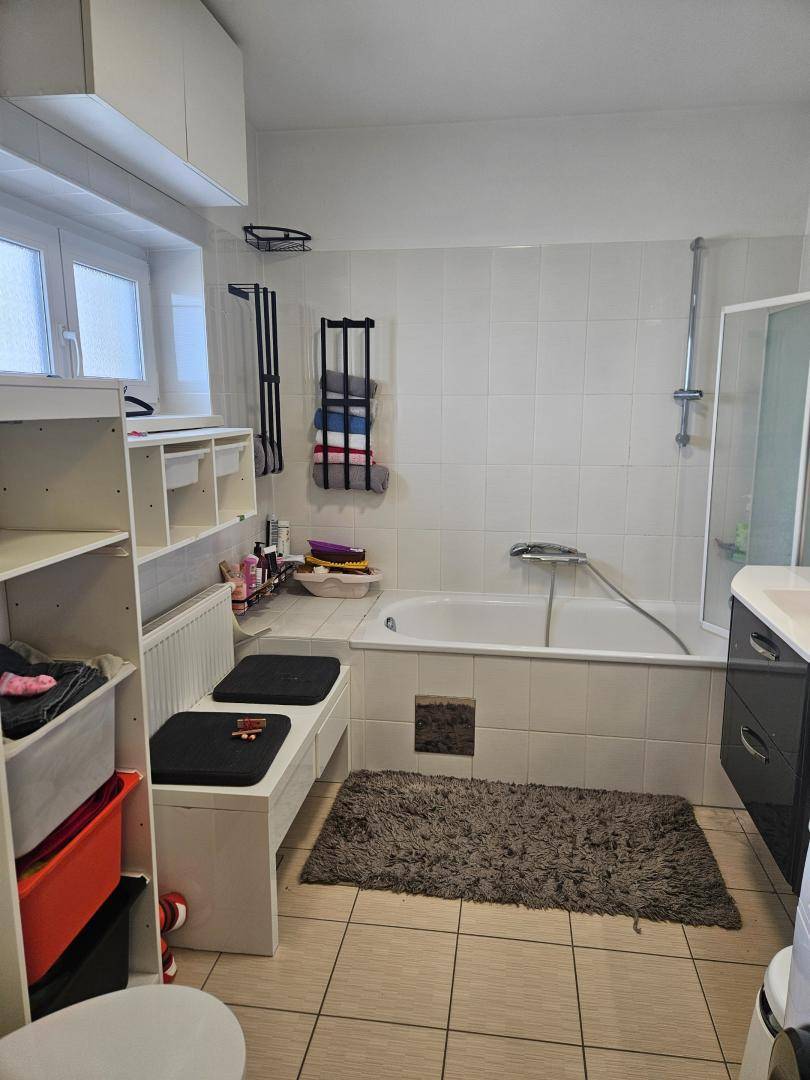 Helles Badezimmer mit Badewanne, Dusche und Fenster für Tageslicht.