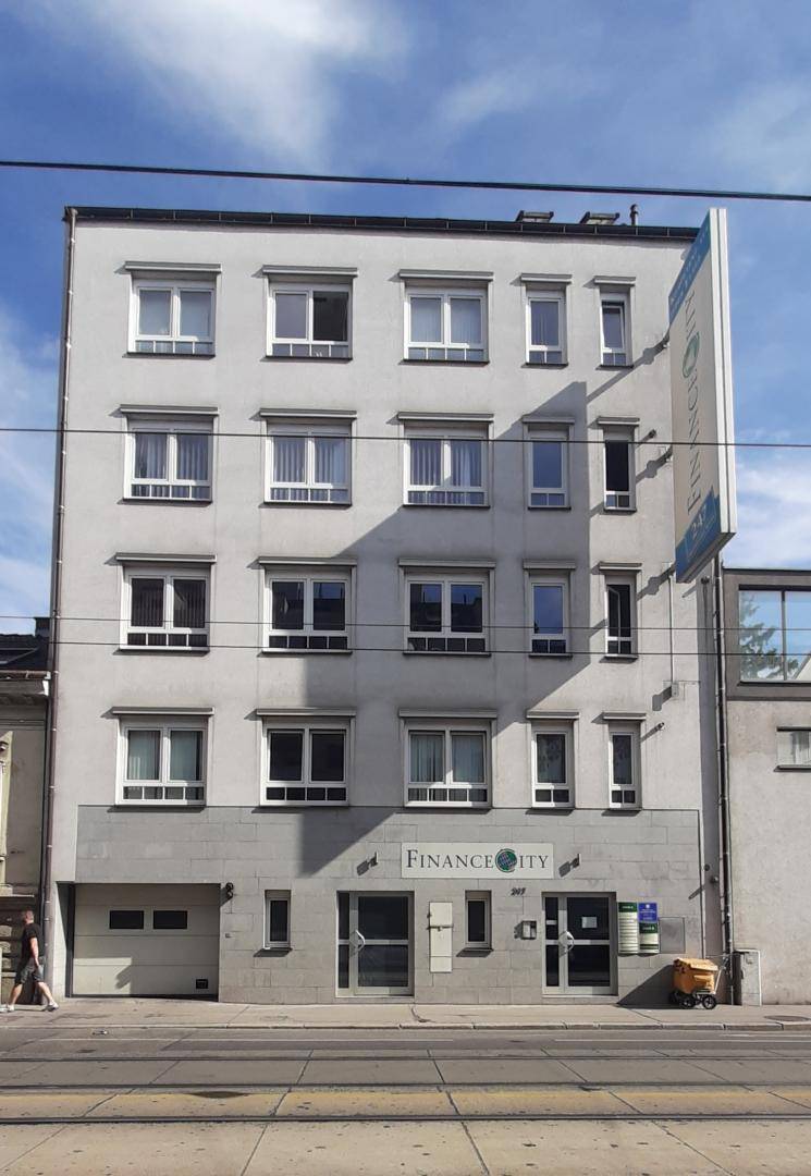 Modernes Geschäftsgebäude mit mehreren Etagen, großen Fenstern und einer Werbetafel an der Fassade.