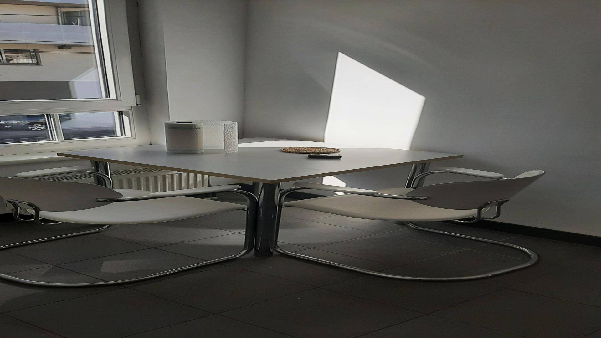 Kleiner Essbereich mit modernem Tisch und Stühlen, beleuchtet durch Sonnenlicht, das durch das Fenster fällt.