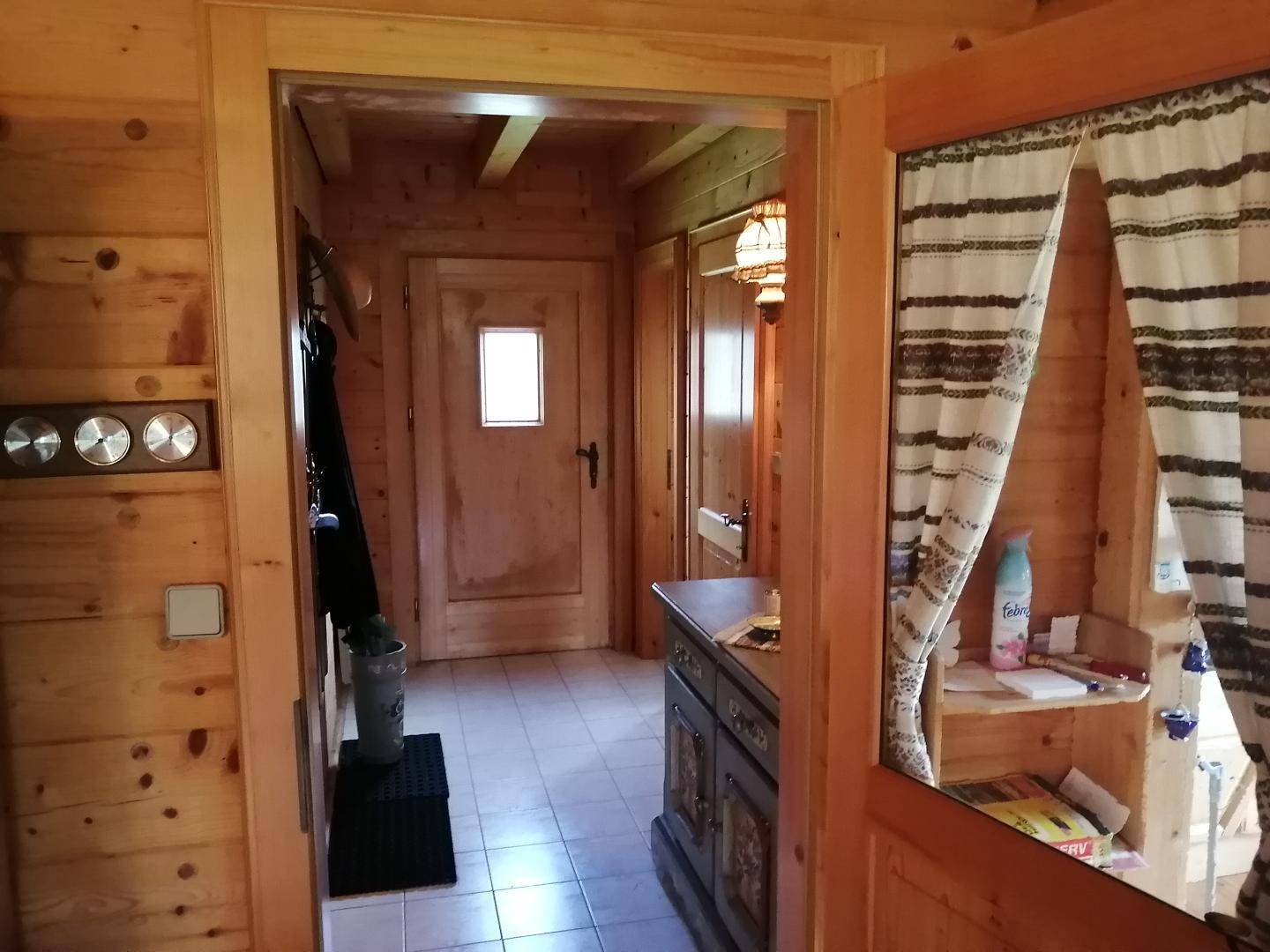 Eingangsbereich mit Holzwänden, Fliesenboden und einem traditionellen Holzschrank mit Dekoration.