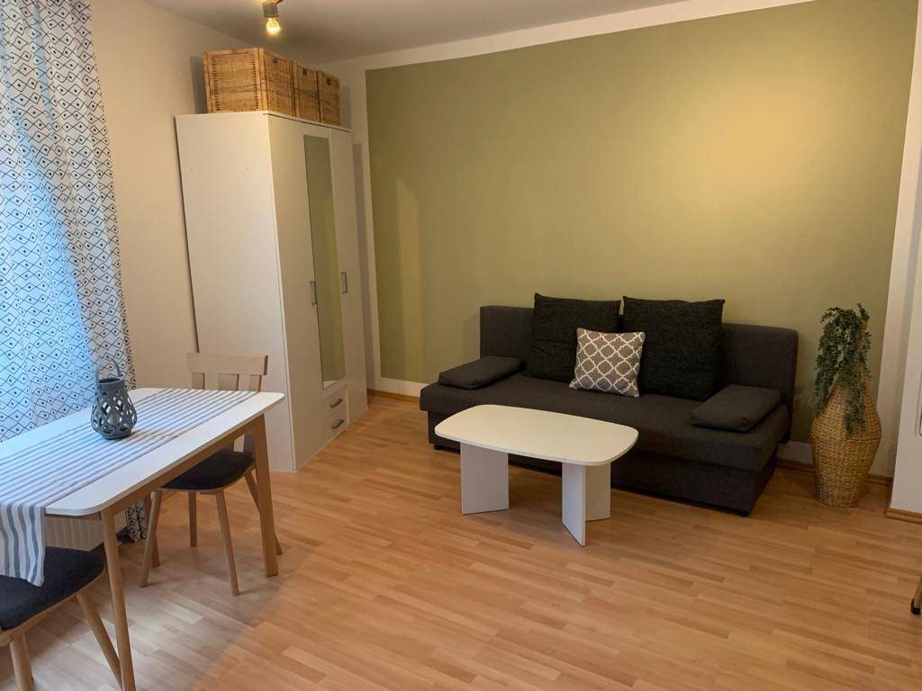 Wohn- und Essbereich mit Sofa, Esstisch und hellem Laminatboden.