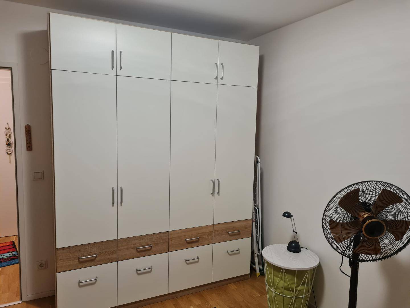 Schlafzimmer mit großem Kleiderschrank in Weiß und Holzoptik.