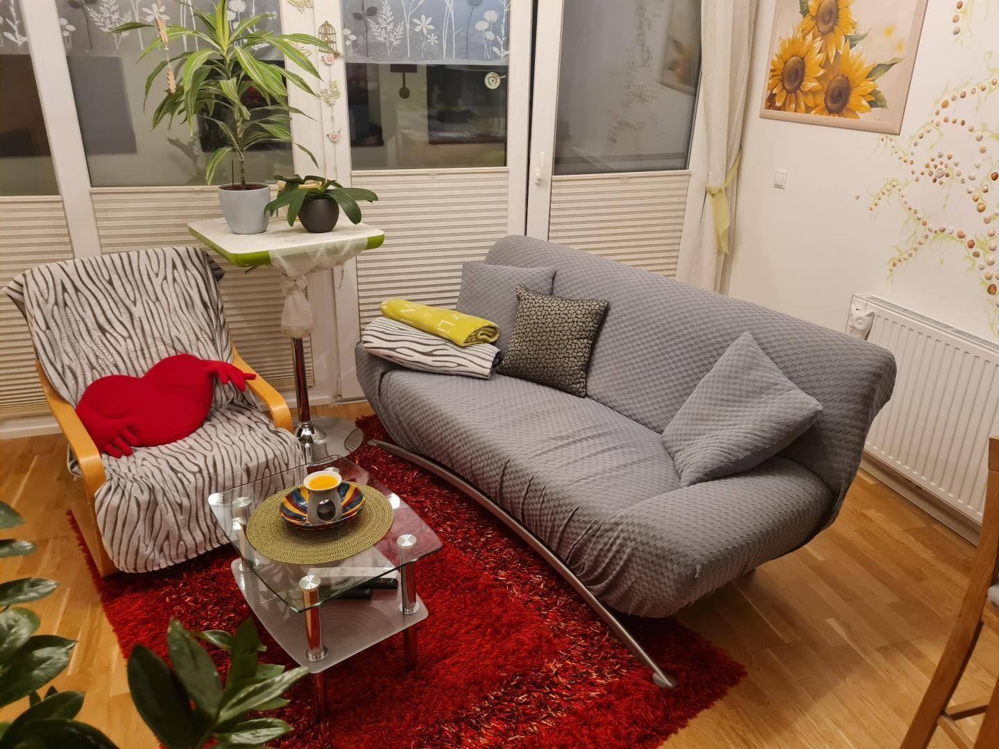 Gemütlicher Wohnbereich mit Sofa, Sessel, rotem Teppich und Zugang zur Loggia.