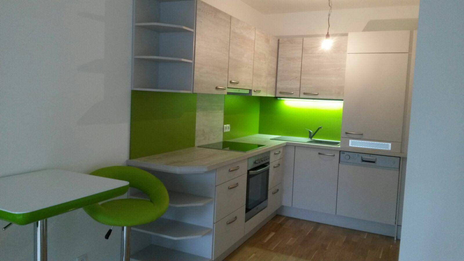 Moderne Küche mit hellen Schränken, grüner Rückwand und integrierten Geräten.