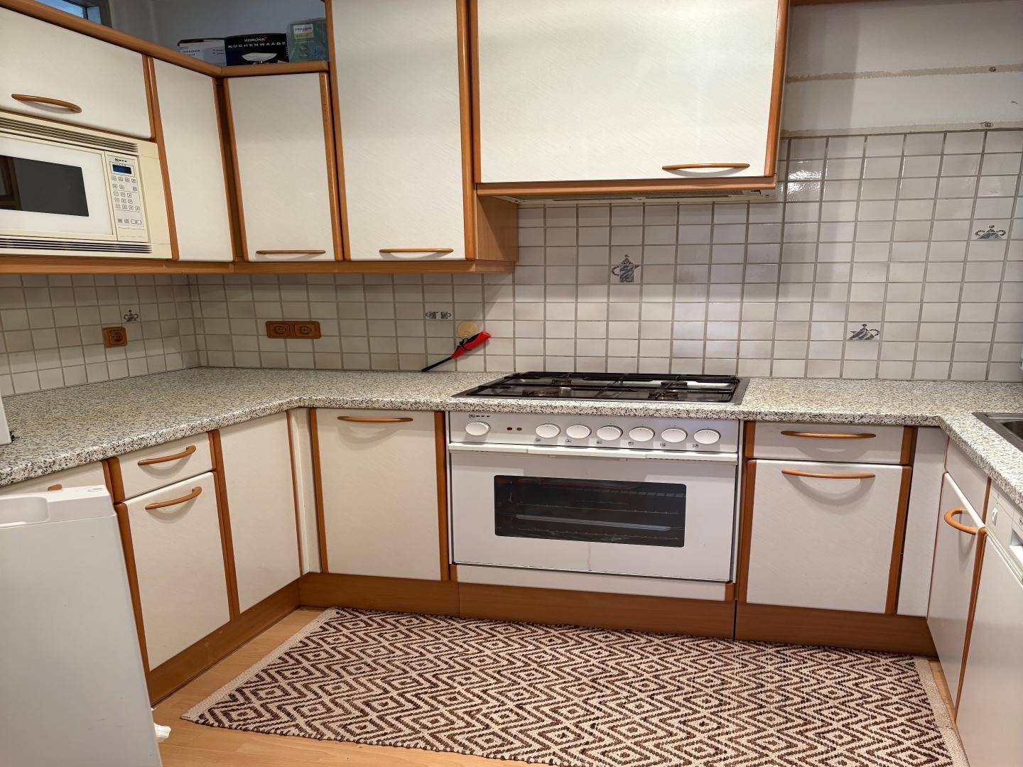 Funktionale Küche mit Gasherd, Mikrowelle und gefliestem Spritzschutz.