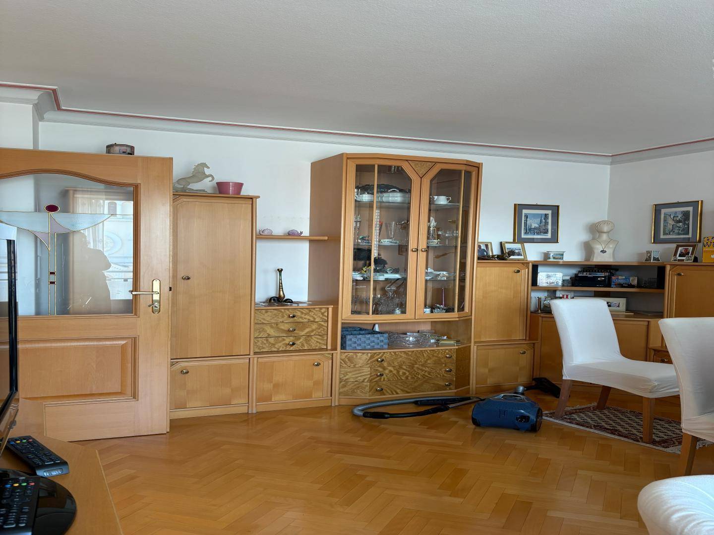 Gemütliches Wohnzimmer mit Fischgrätparkett, Holzmöbeln und traditioneller Einrichtung.
