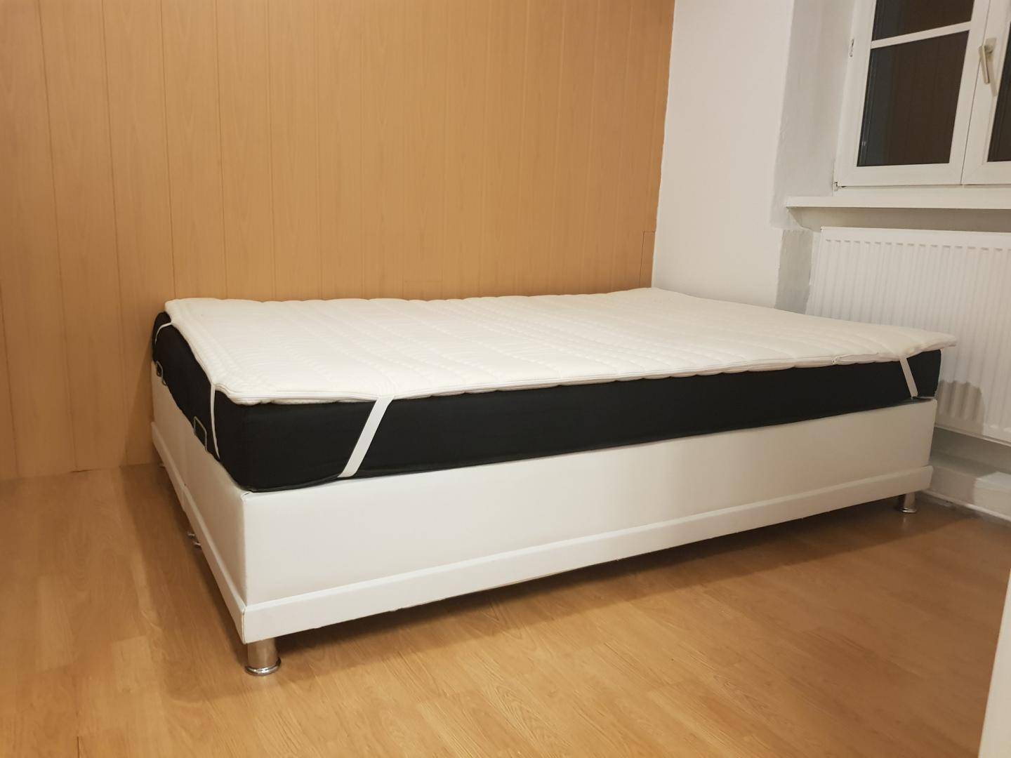 Helles Schlafzimmer mit Holzboden, einer Holzwandverkleidung und hohen Decken.