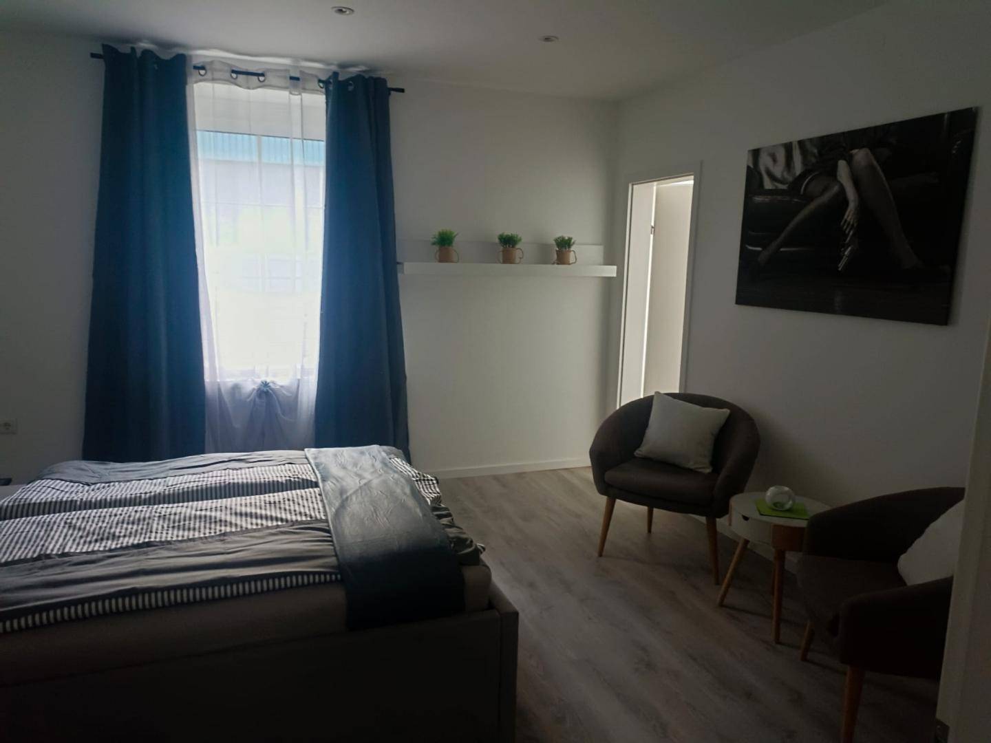 Helles Schlafzimmer mit großem Fenster, zwei Einzelbetten und bequemen Sesseln.