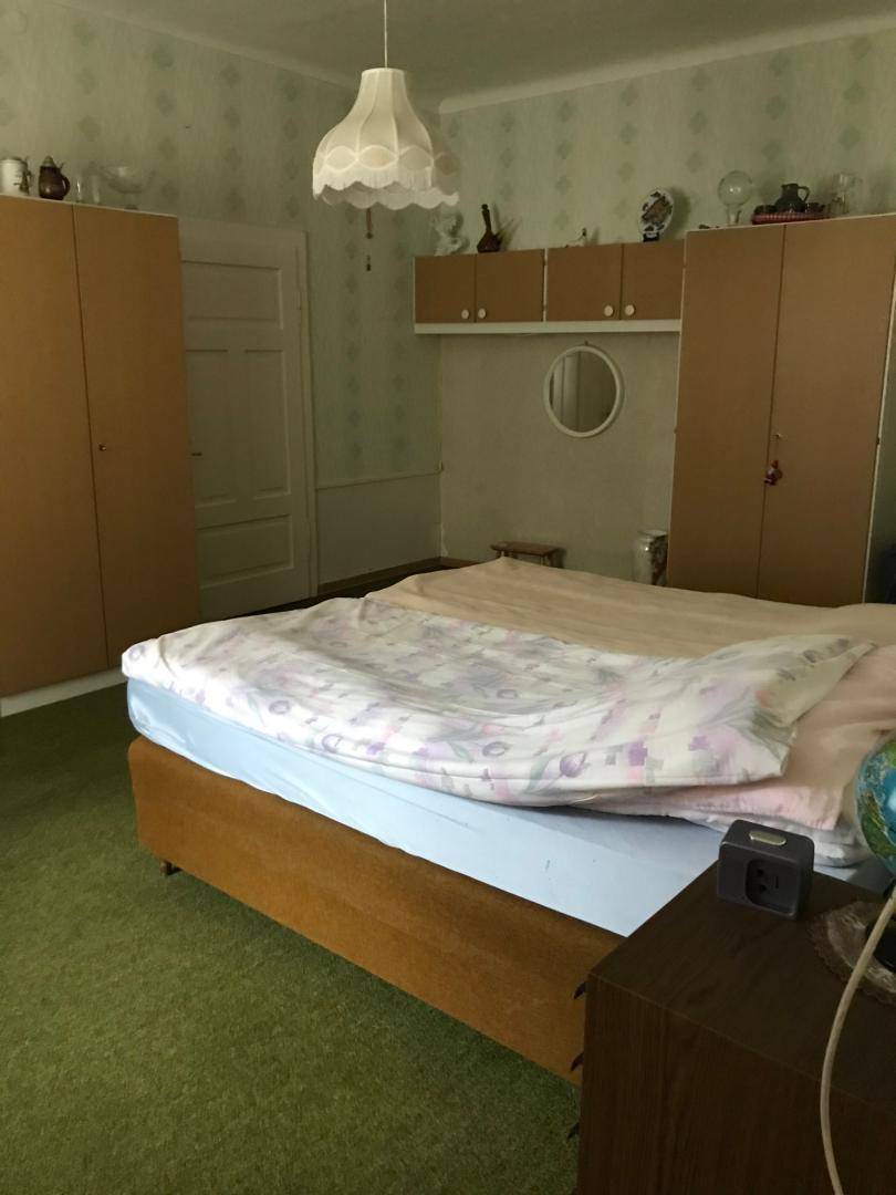 Schlafzimmer mit Doppelbett, Kleiderschränken und gemusterter Tapete.