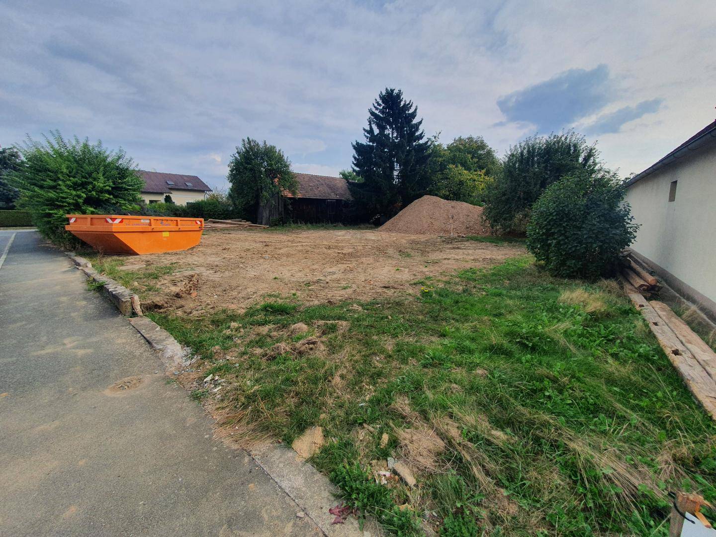 Leeres Baugrundstück mit Erdhaufen und einem Container, bereit für die zukünftige Bebauung.