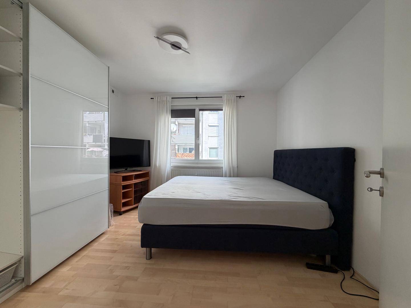 Helles Schlafzimmer mit Doppelbett, weißem Kleiderschrank und Holzboden.