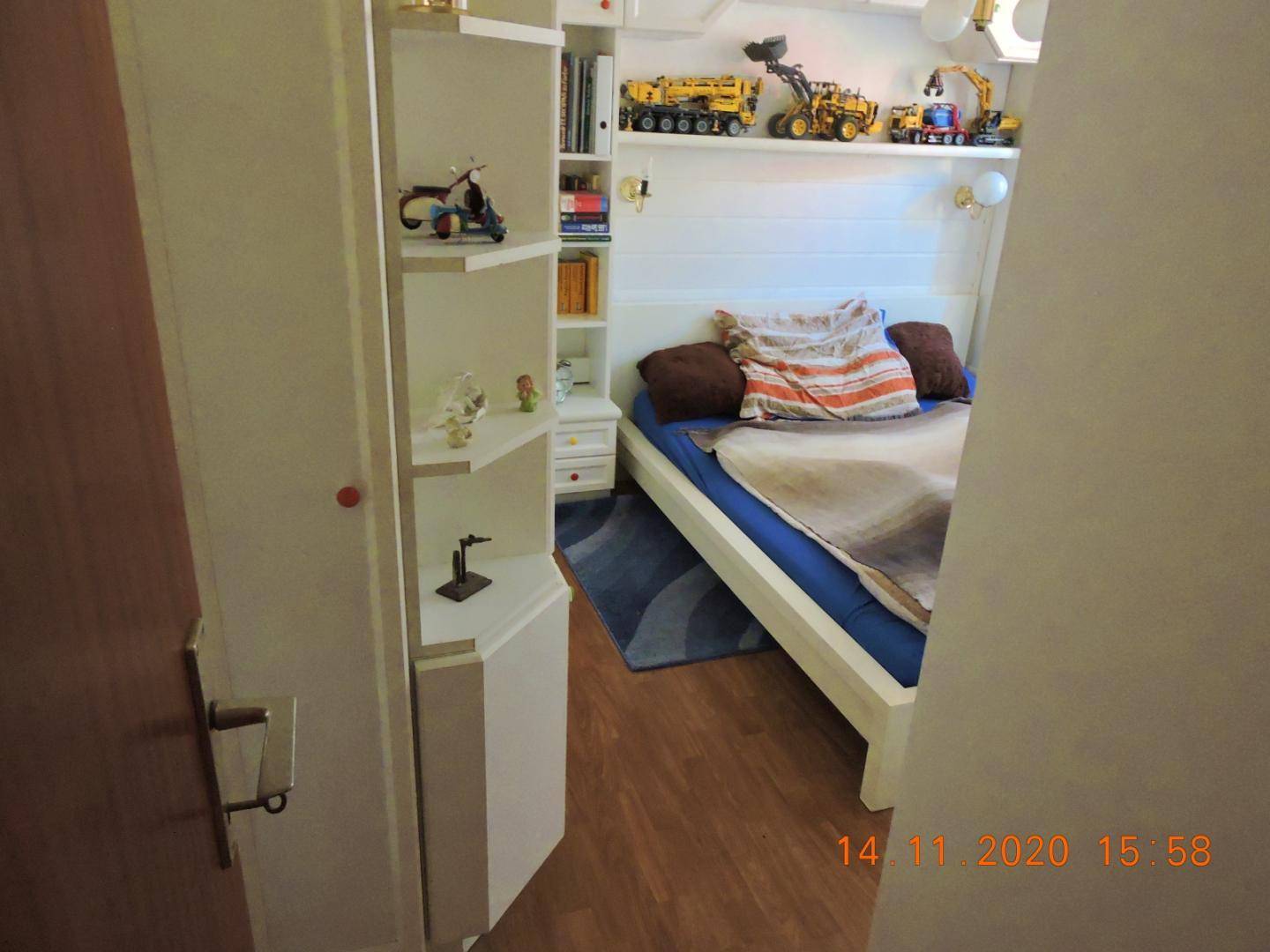 Schlafzimmer mit Einzelbett, weißen Regalen und Spielzeugdekoration.