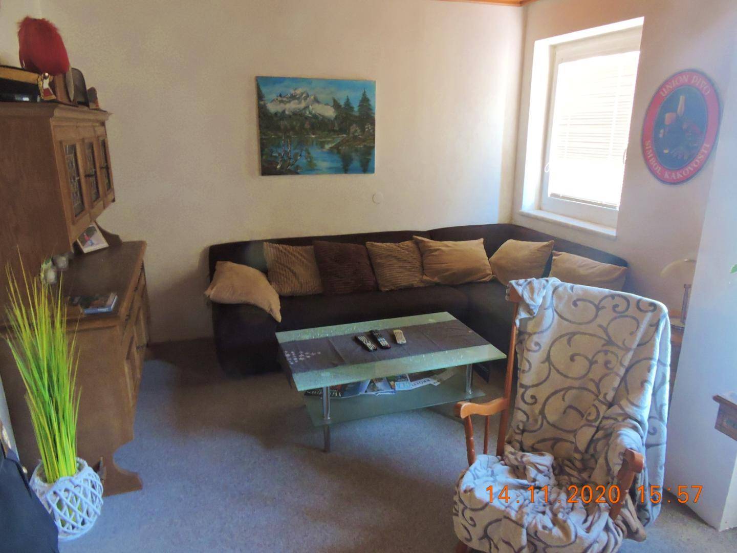 Gemütliches Wohnzimmer mit dunklem Sofa, Couchtisch und traditionellen Holzmöbeln.
